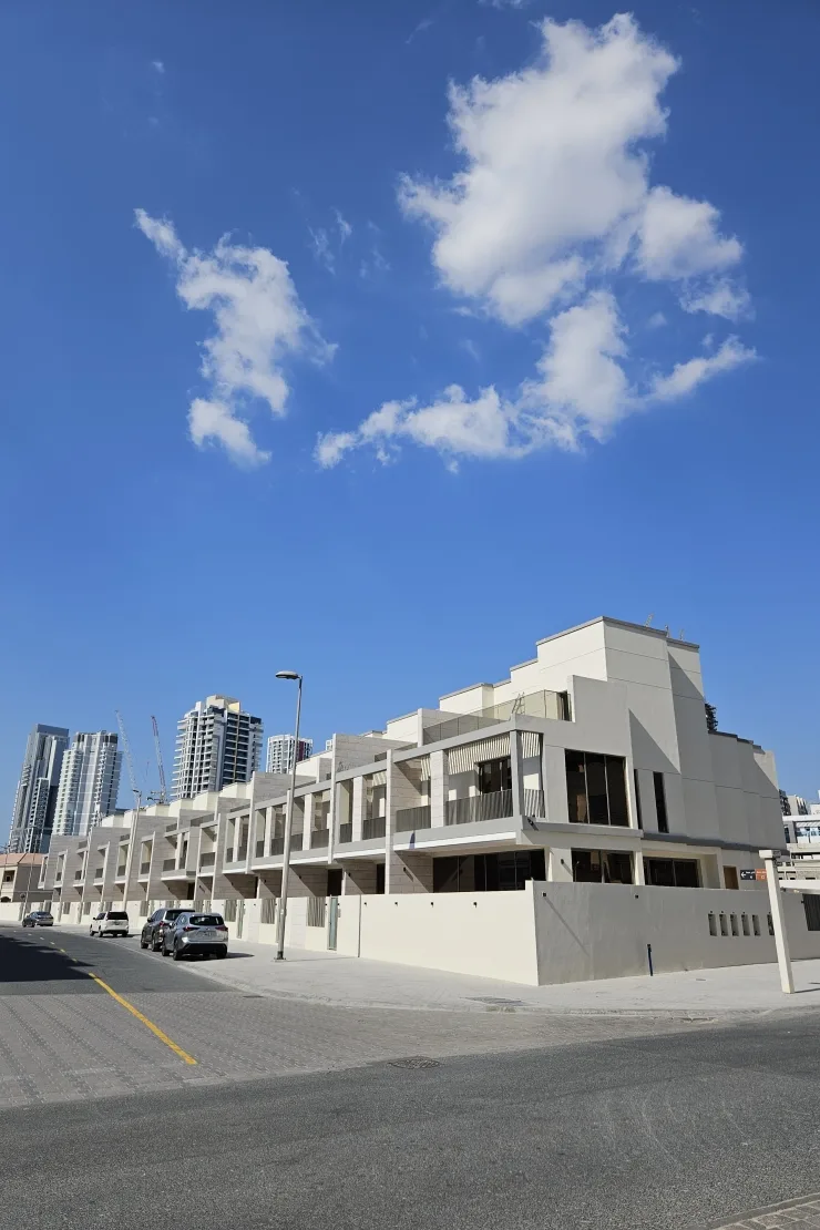 Completed townhouse row from street corner, blue sky