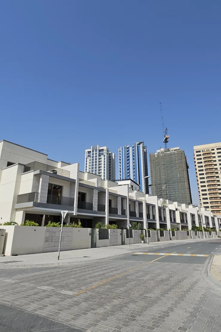 Completed townhouse row along street with towers behind