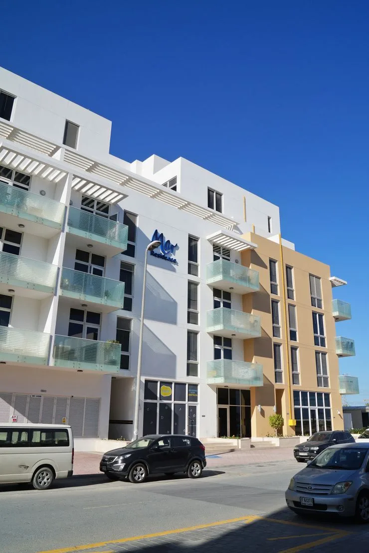 Low-rise white and tan building with glass balconies, Mar sign