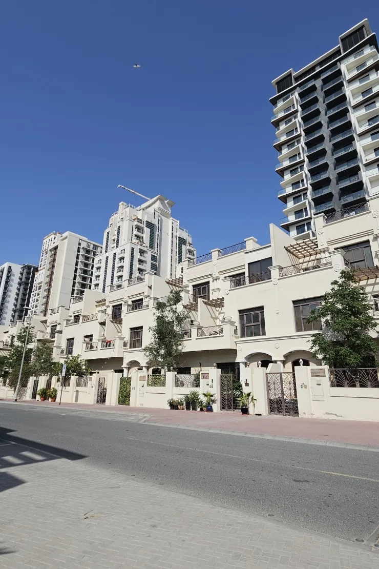 Cream townhouse row with arched entrances and pergolas