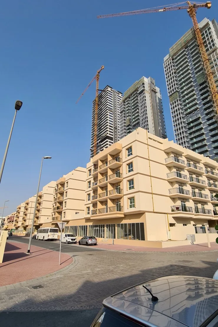 Street view of beige block, towers behind