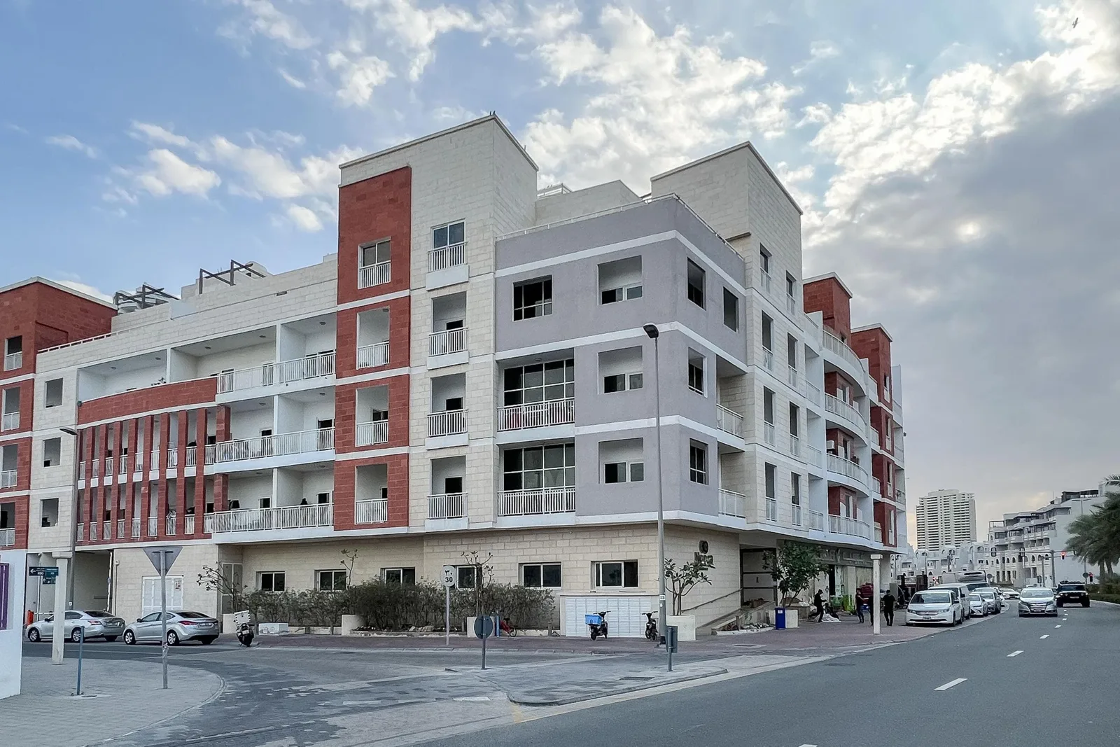 Corner view of full low-rise building with red and grey facade
