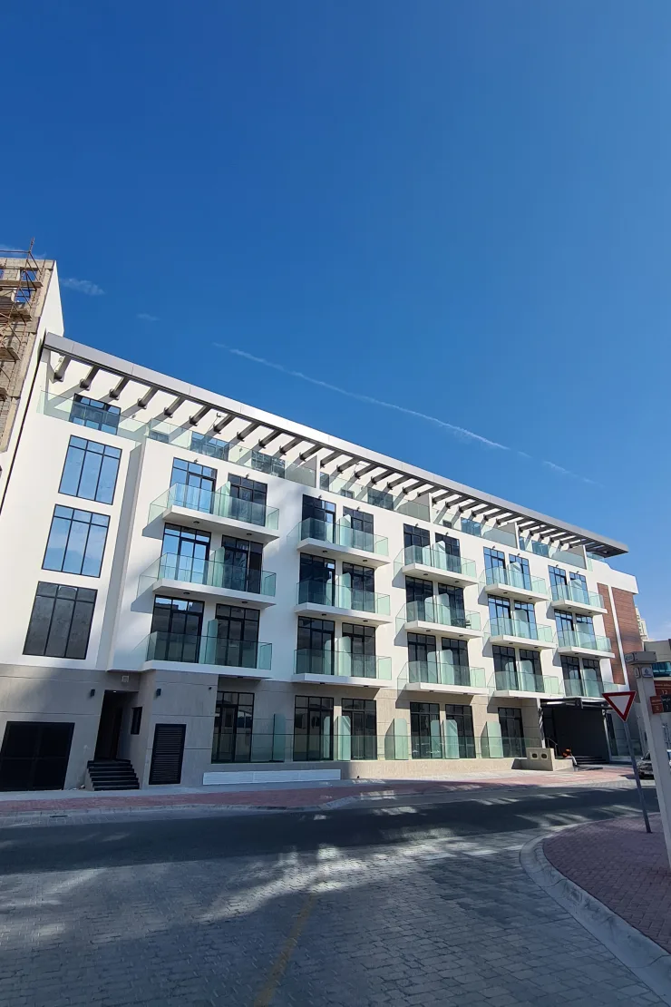 Completed white building with pergola roof and glass balconies