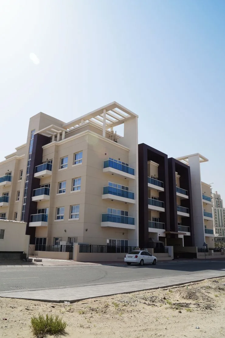 Low-rise beige residential building with blue glass balconies