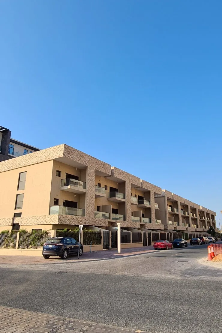 Completed low-rise block with stone-clad balconies, street view