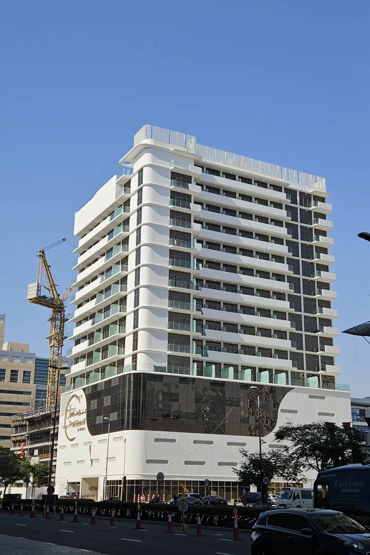 Completed white tower with curved balconies and dark podium