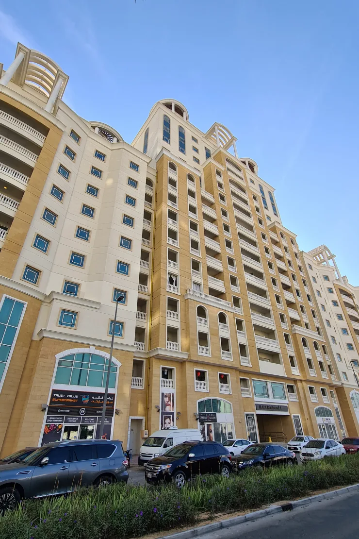 Ground-up view of tower, beige facade, shops