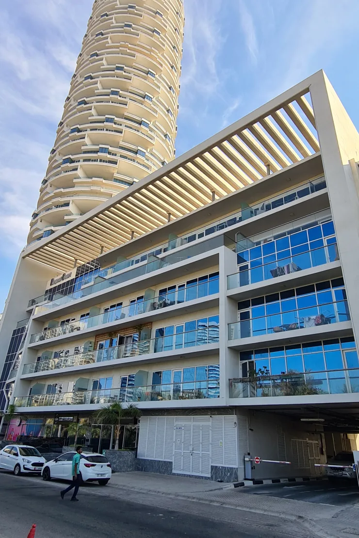 Street view of glass-balconied building and pergola