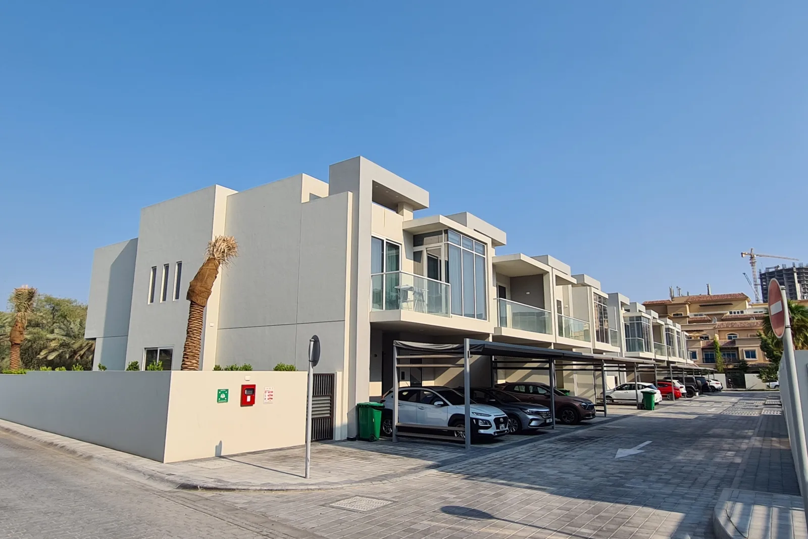 Townhouse row with carports, grey-beige facade, street view