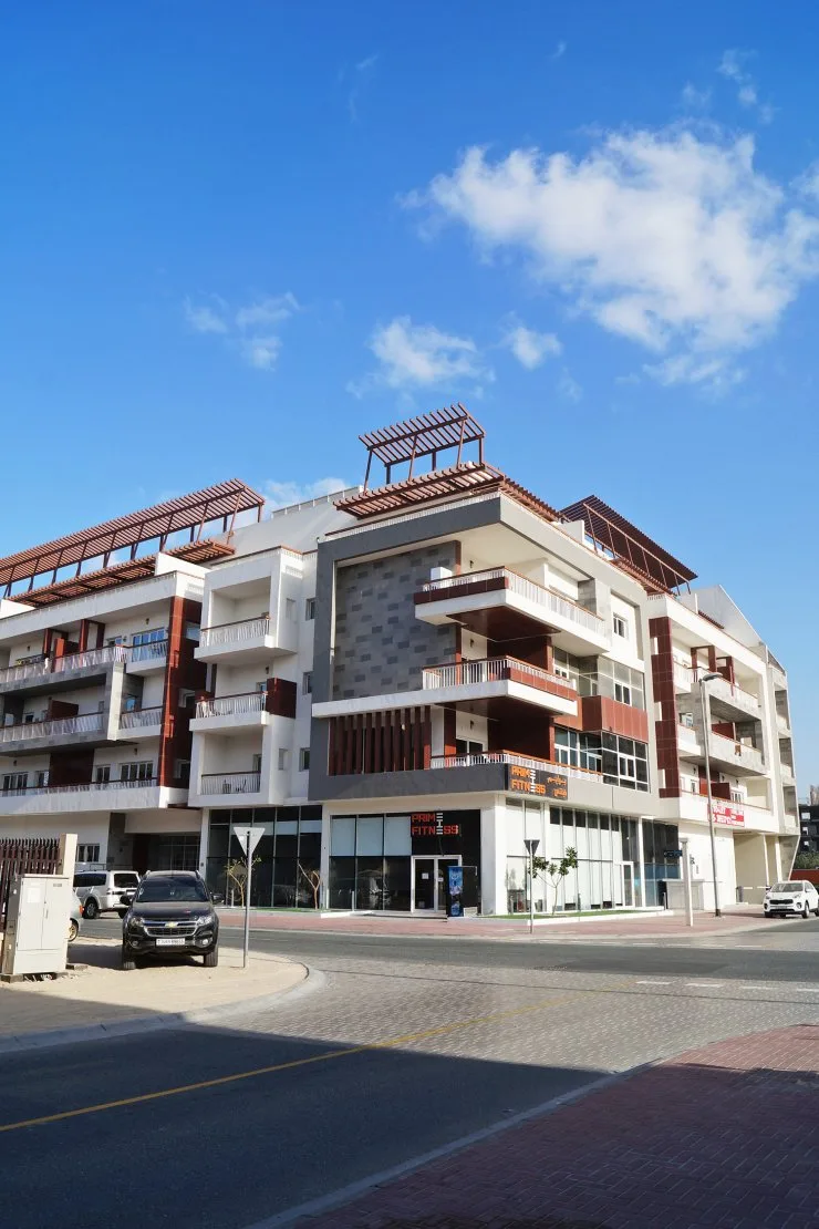 Completed mid-rise corner building with terracotta accents and pergolas