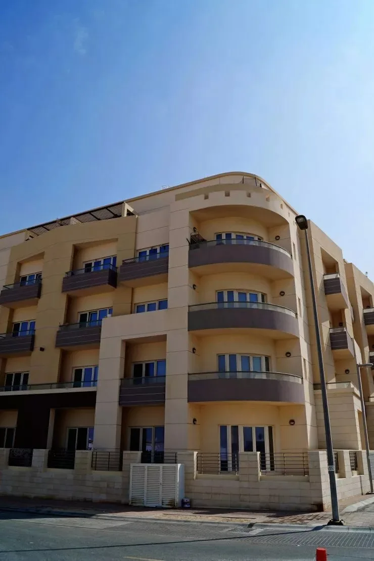 Curved-balcony beige apartment block seen from the street