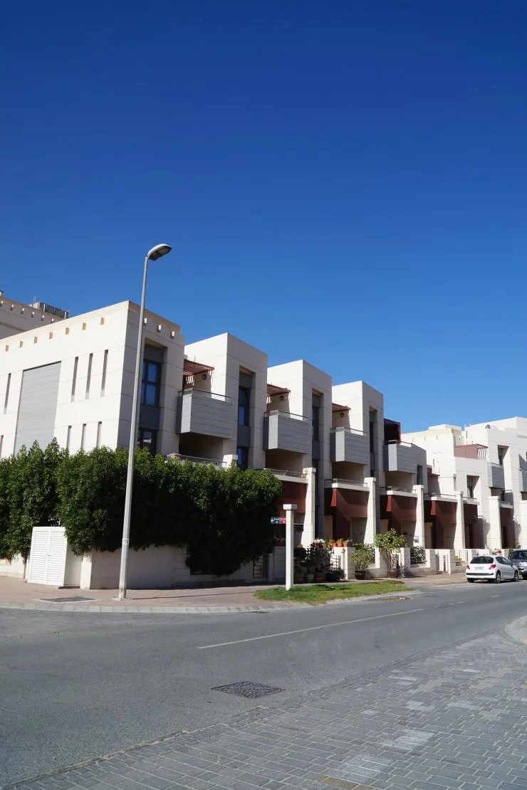 Cream stepped townhouse row with grey balconies, street view