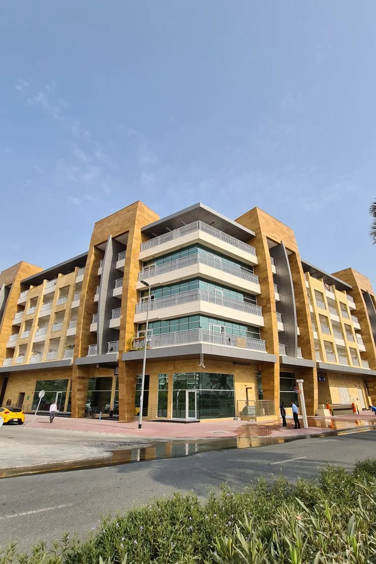 Completed sandstone-clad building with balconies, street view