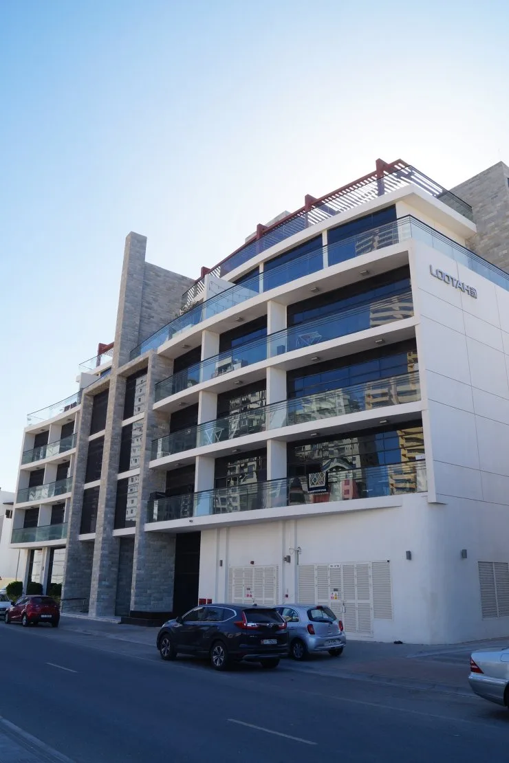 Street-level view of stone fins and glass balconies