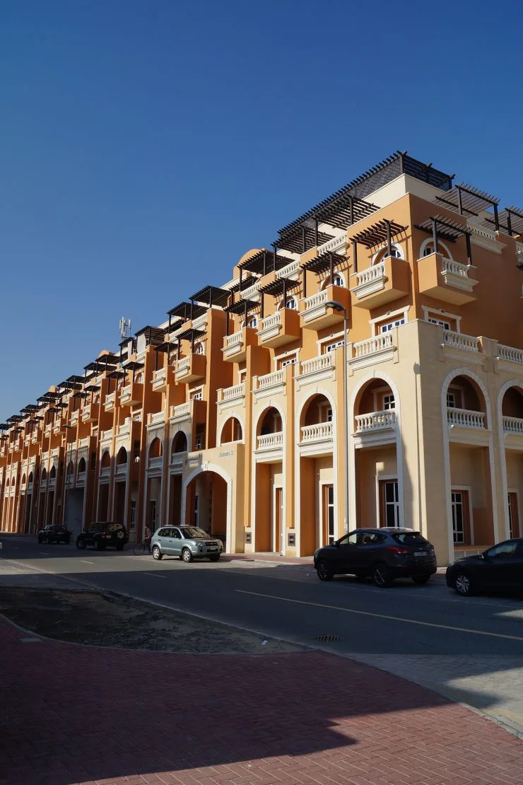 Long orange facade with pergolas along street
