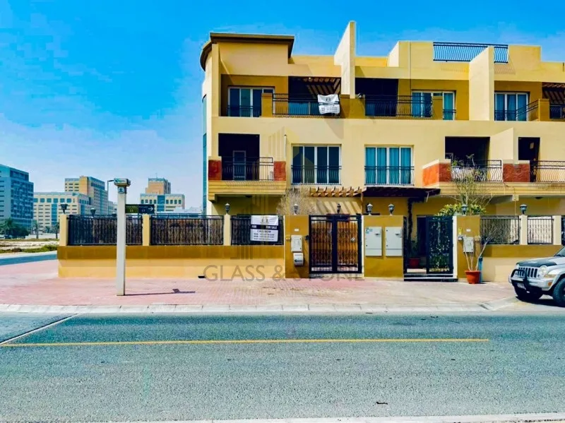 Corner townhouse block with yellow facade and gates