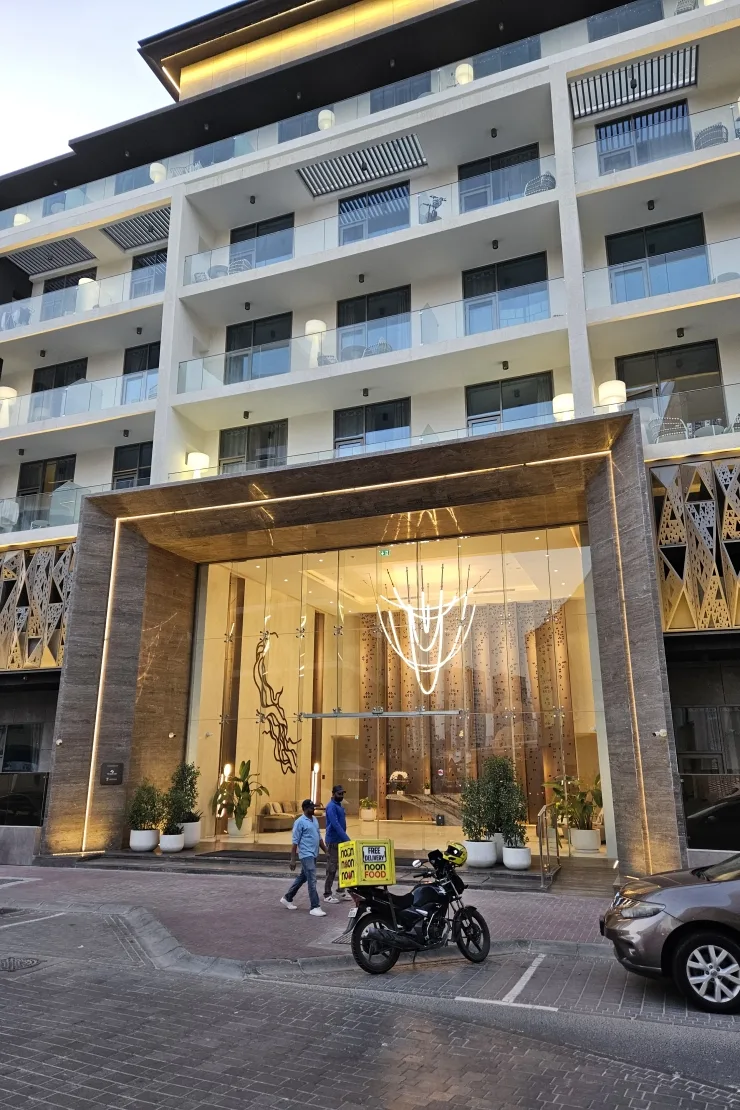 Glass entrance canopy and balconies, lit at dusk
