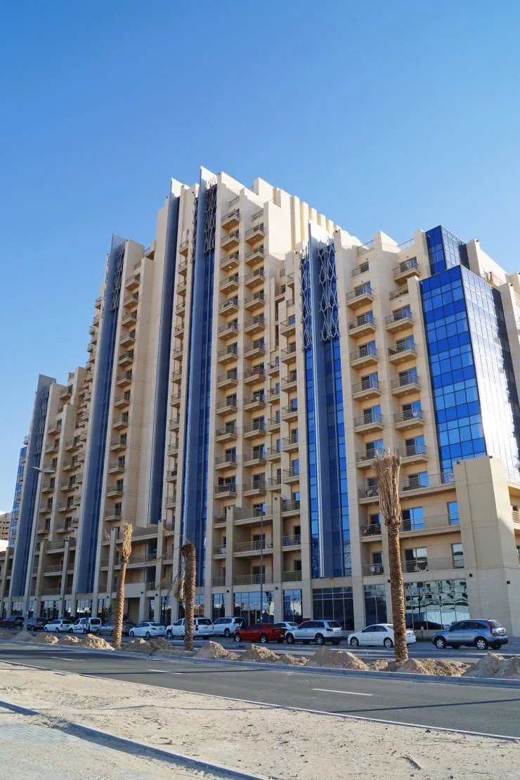Full beige tower with blue glass bays, street view