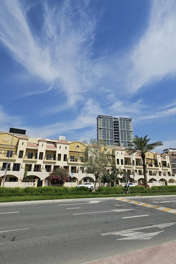 Cream arcaded townhouse-style block along street, tower behind
