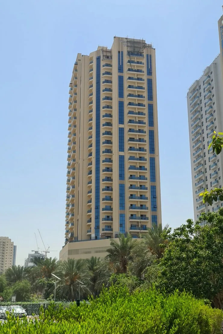 Tower seen from street through palms and greenery