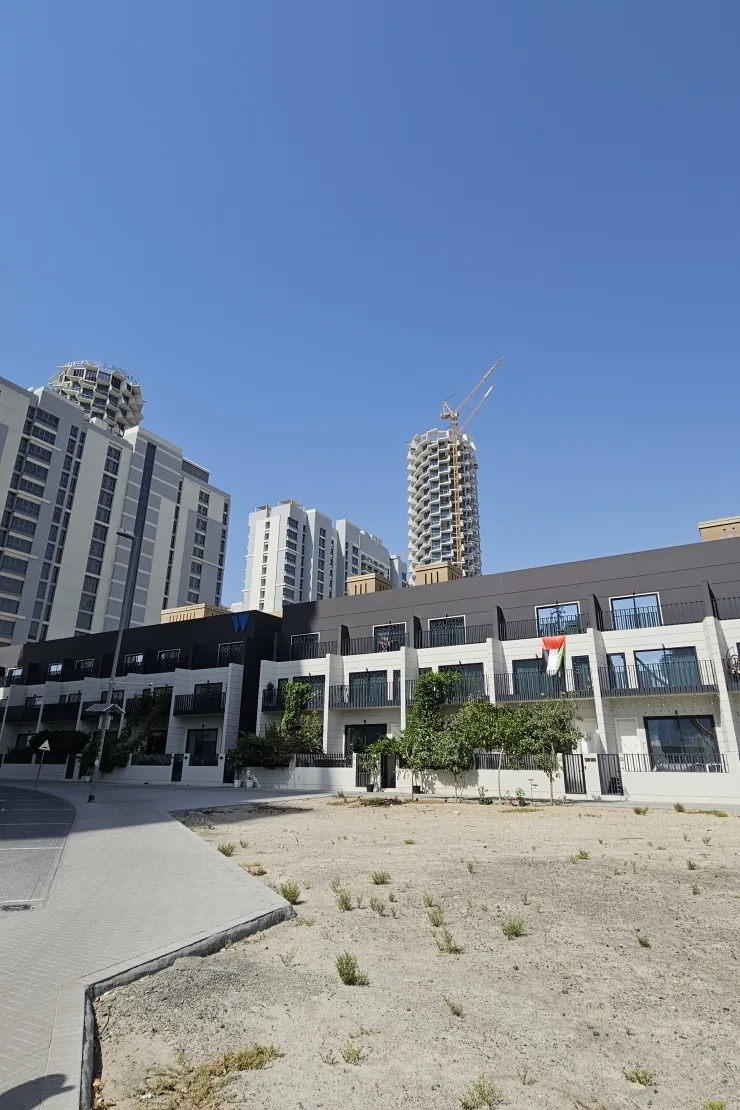 Townhouse block with W logo, balconies, towers behind