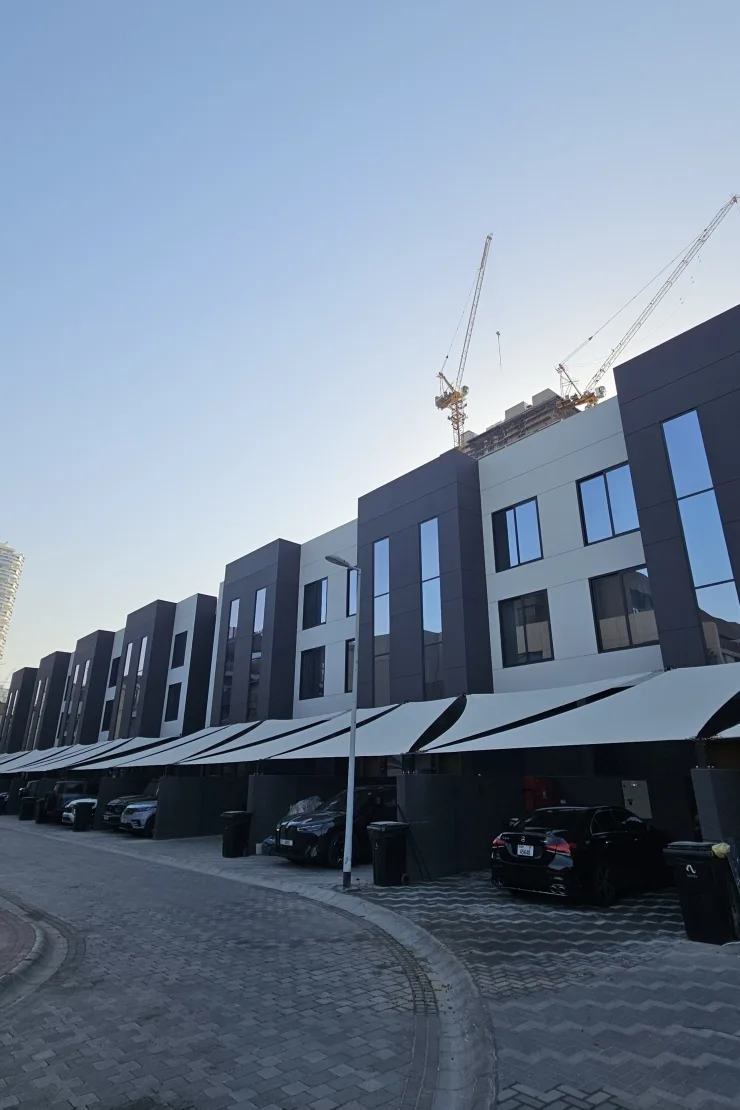 Dark-paneled townhouse row with shaded parking