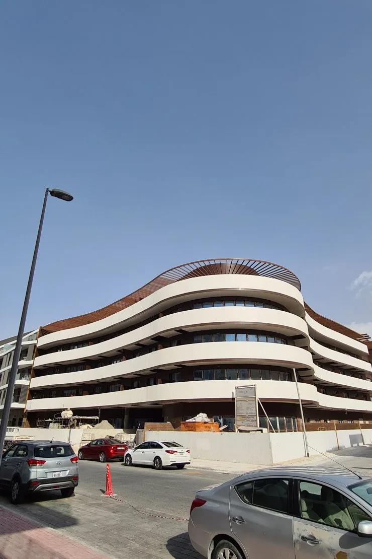 Corner view of curved balconies and louvred crown
