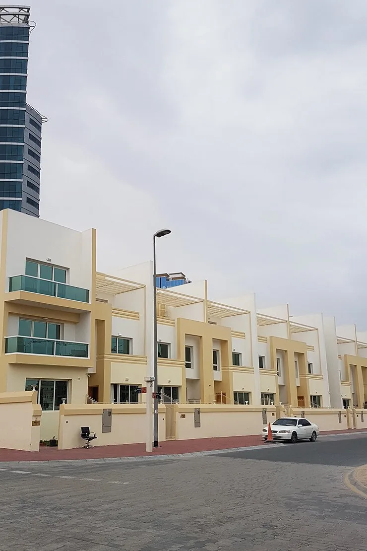 Yellow townhouse row with glass balconies, street view